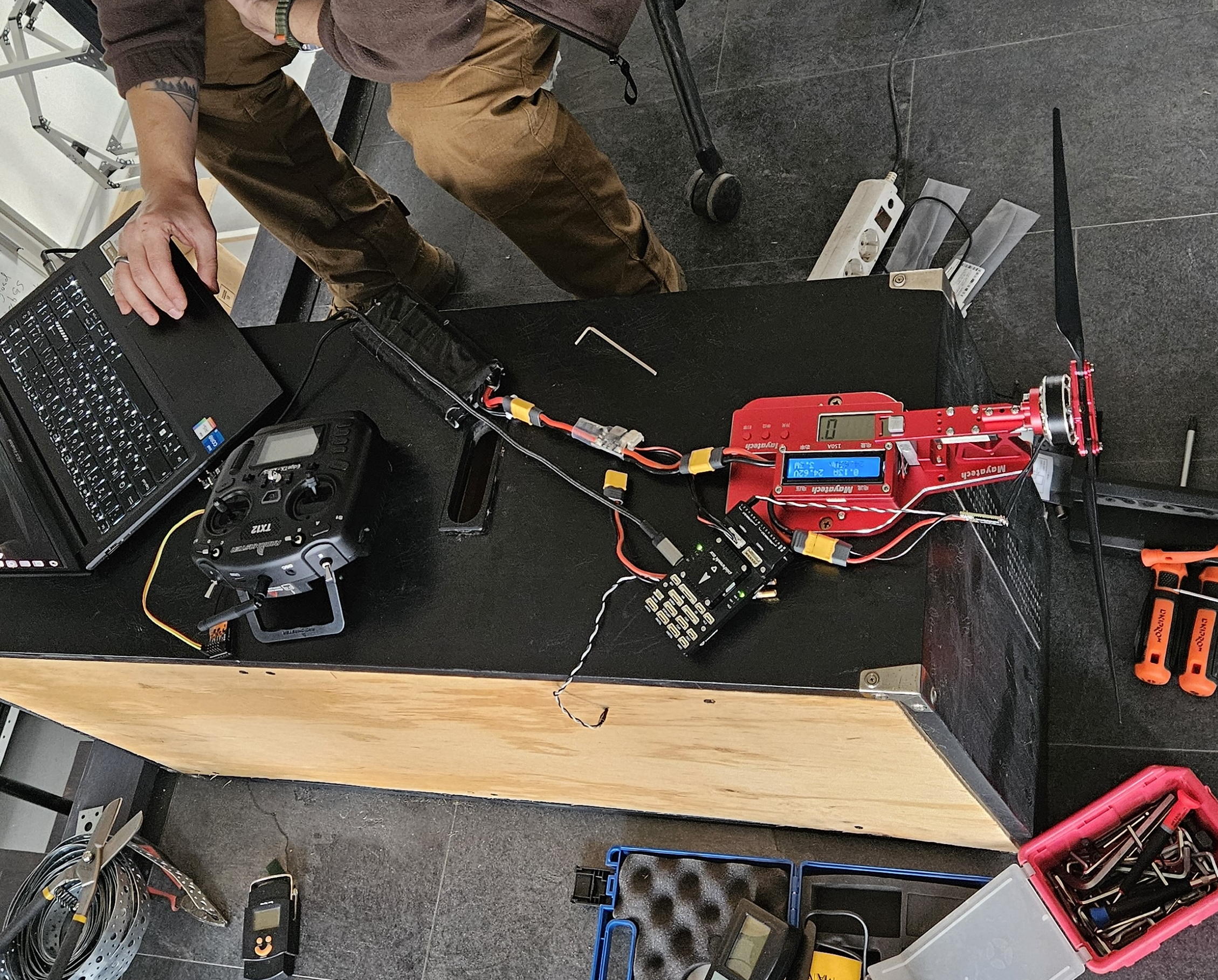 A Black Forest employee sits in front of a laptop at a workbench containing various drone parts and tools