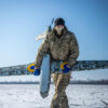 An operator carries a Ukrspecsystems UAV over snow-covered ground against a blue sky.