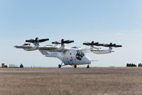 A white Vertical Aerospace VX4 eVTOL prototype sits on a paved surface against a pale blue sky