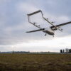 Rear view of the ERC eVTOL prototype "Romeo" in a high hover over a grass test area against a cloudy sky