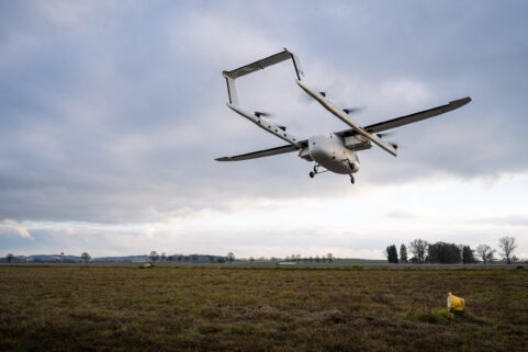 Rear view of the ERC eVTOL prototype "Romeo" in a high hover over a grass test area against a cloudy sky